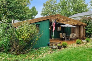 A captivating house facade surrounded by a lush green landscape, nestled in the midst of a wide-open space adorned with an abundance of plants and trees. The verdant surroundings enhance the charm of the green house, creating a harmonious blend of ar
