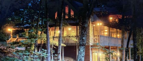 View of the cabin from the fire pit at sunset with the lights on inside.  