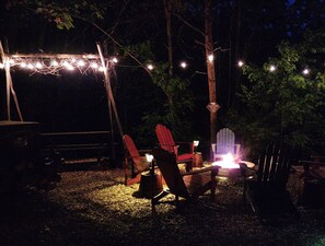Cozy fire pit with plenty of seating, a grill, and lights!