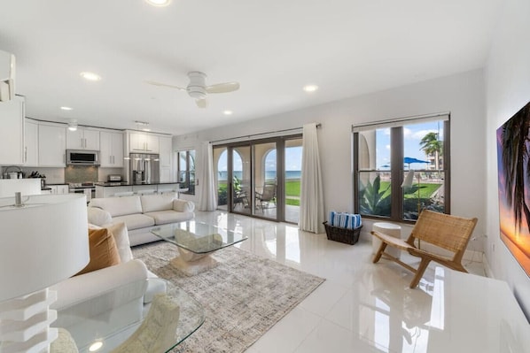 Relax in our inviting living room, which opens up to a scenic view of the sparkling pool, the expansive ocean, and a beautifully landscaped, lush grassy area, blending indoor comfort with outdoor beauty