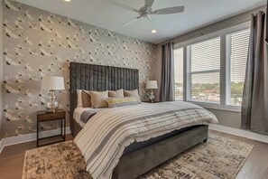 *This third floor primary suite includes custom wallpaper, walk in closet, large smart tv, and full en suite bath.