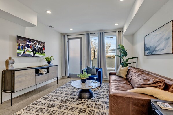 Open-concept living space featuring a comfortable sectional with a Smart TV for entertainment and a fully equipped kitchen stocked with all culinary essentials and stainless steel appliances.