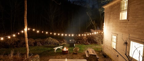 Stone patio with BBQ grill, 2 picnic tables, fire pit, firewood