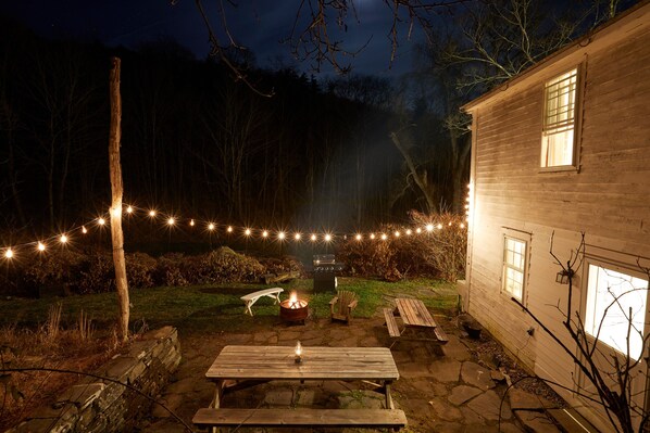 Stone patio with BBQ grill, 2 picnic tables, fire pit, firewood