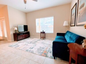Relax in the spacious living room, featuring comfortable seating, a large flat-screen TV