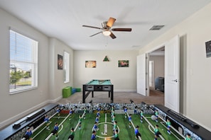 Fun game room with foosball, pool table, and bright natural light.