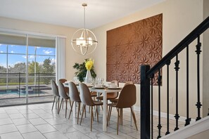 Elegant dining area with modern accents and views of the pool and greenery.