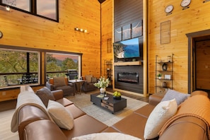 This cabin offers a spacious, cozy living room with large windows framing stunning views of the Smoky Mountains.