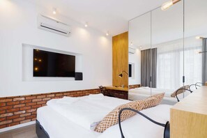 Bedroom area, showing the bed, wooden panel wall details, and a contemporary decor style. On a wall is a big TV.