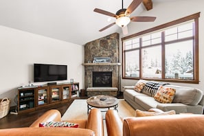 Living room with vaulted ceilings, stone fireplace and flatscreen TV.