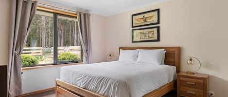 The elegantly appointed primary bedroom, with views overlooking the garden, features a king-size bed and an ensuite for added convenience.