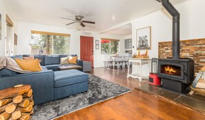 Living room open to the kitchen/dining area. Fireplace with firewood provided.