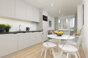 A sleek kitchen with white cabinetry, a round dining table, and modern appliances.
