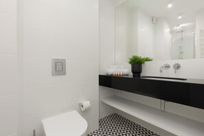 A minimalist bathroom with white walls, a floating vanity, and a large mirror.
