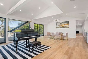 grand piano as its centerpiece. Large windows invite natural light and scenic views, while the spacious dining area and modern decor create an inviting ambiance. Perfect for music lovers :)