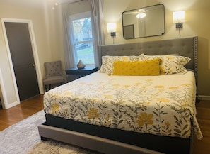 Main floor bedroom with king bed, TV, and an attached half bath