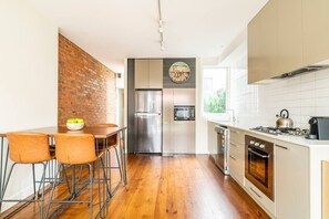 Kitchen equipped with coffee machine, saucepans, dinnerware & basic condiments.