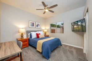 Primary bedroom with queen-size bed, smart TV, and dedicated workspace