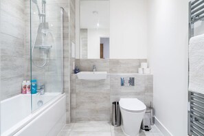 Modern fitted bathroom with tub and overhead shower