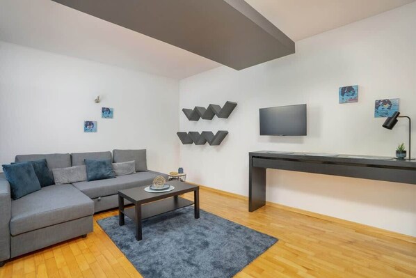 A cozy living room featuring a gray sofa, wall-mounted TV, and modern decor, creating a relaxed ambiance.