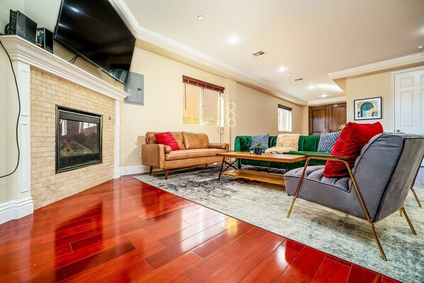 Large living room with seating for 8, pool table, and large 75 inch smart TV