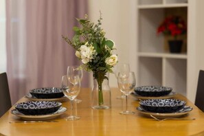 A beautifully set dining table with black plates, gold cutlery, and fresh flowers, enhancing the dining experience with a touch of elegance.
