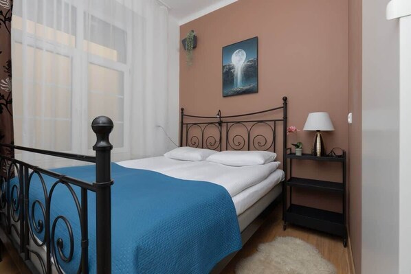 A cozy bedroom with a wrought iron bed, blue bedding, and soft lighting, creating a charming and restful sleeping space.
