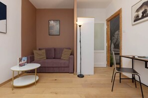A living area with a purple sofa, wooden flooring, and minimalist decor, maintaining a modern and comfortable atmosphere.

