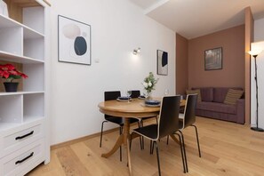 A dining area with a round wooden table, black chairs, and minimalist decor, offering a functional and elegant dining space.
