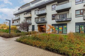 An exterior view of the apartment building surrounded by greenery and landscaped gardens.
