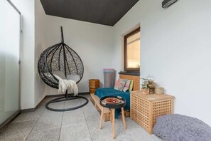 A charming balcony with a hanging chair, wicker furniture, and a serene atmosphere.
