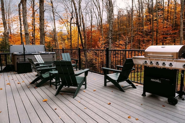 Deck with a premium hot tub, adirondack seating, grill and views of the Vermont forest