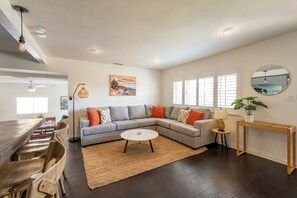 Living room features a large L-sofa, Roku TV, and board games 
