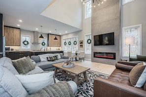 Step into the heart of comfort with a massive open-concept great room, adorned with plush, comfy furniture and bathed in the warm glow of the fireplace centerpiece.