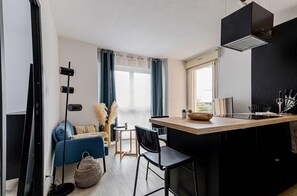 Une pièce à vivre avec canapé, télé, coin repas et cuisine ouverte. Petit...