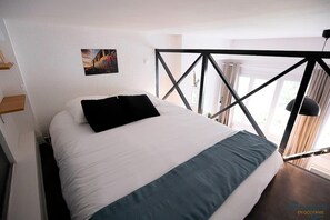 Mezzanine accessible par une échelle avec un lit double et placard de rangement
