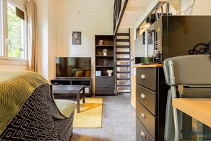 Pièce à vivre avec coin bureau, télé et canapé et quelques rangements