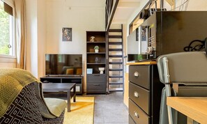 Pièce à vivre avec coin bureau, télé et canapé et quelques rangements
