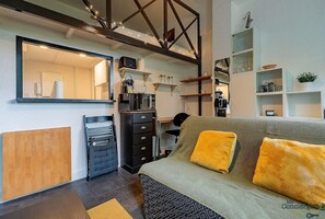Pièce à vivre avec coin bureau, télé et canapé, cuisine et quelques rangements
