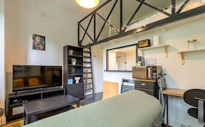 Pièce à vivre avec coin bureau, télé et canapé et quelques rangements