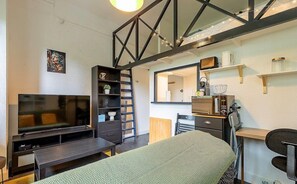 Pièce à vivre avec coin bureau, télé et canapé et quelques rangements