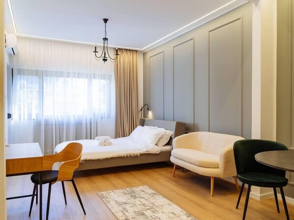 Bedroom/ Living room with a queen sized bed, working desk and dining table for 2, AC, balcony, smart TV and electric exterior blinds 