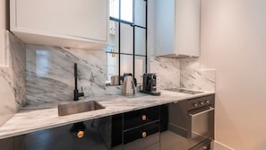 A sleek kitchen with marble finishes, state-of-the-art appliances, and mirrored accents for a modern aesthetic. #LuxuryLiving #ContemporaryStyle