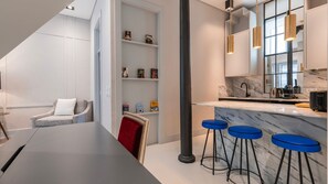 A chic kitchen with a marble breakfast bar, bold blue stools, and pendant lighting for a touch of luxury. #ChicDesign #ModernLiving