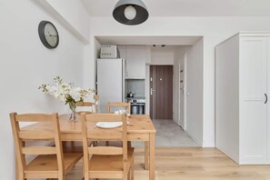 A simple dining nook for four, accented by fresh flowers on the table and leading to a hallway.

