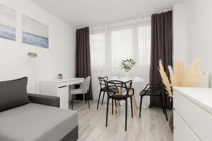 Another angle of the living area, showing the dining space near a large window with sheer curtains.
