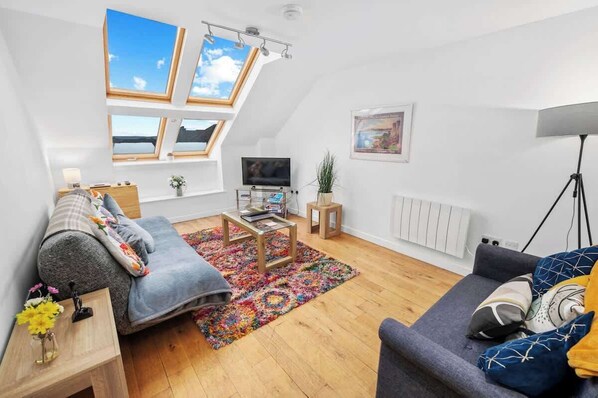 Living area with ample lighting, comfortable seating, and a TV
