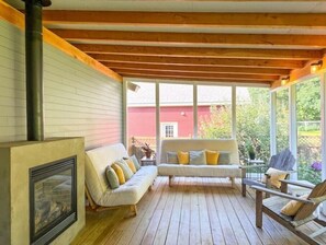 Fireplace and seating area in screen porch.  Futons can convert to outdoor beds!