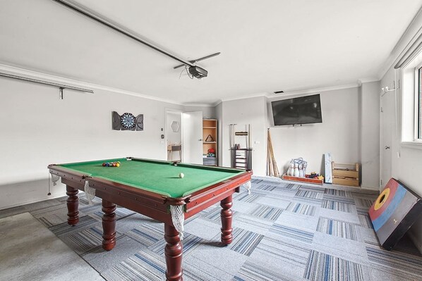 The finished garage acts as a game room and is equipped with a pool table, darts, third TV and access to outside gardens.