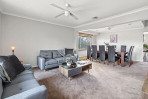 A naturally lit open plan living and dining room offers plenty of seating for the whole group with two comfortable couches and a twelve-seater wooden table.